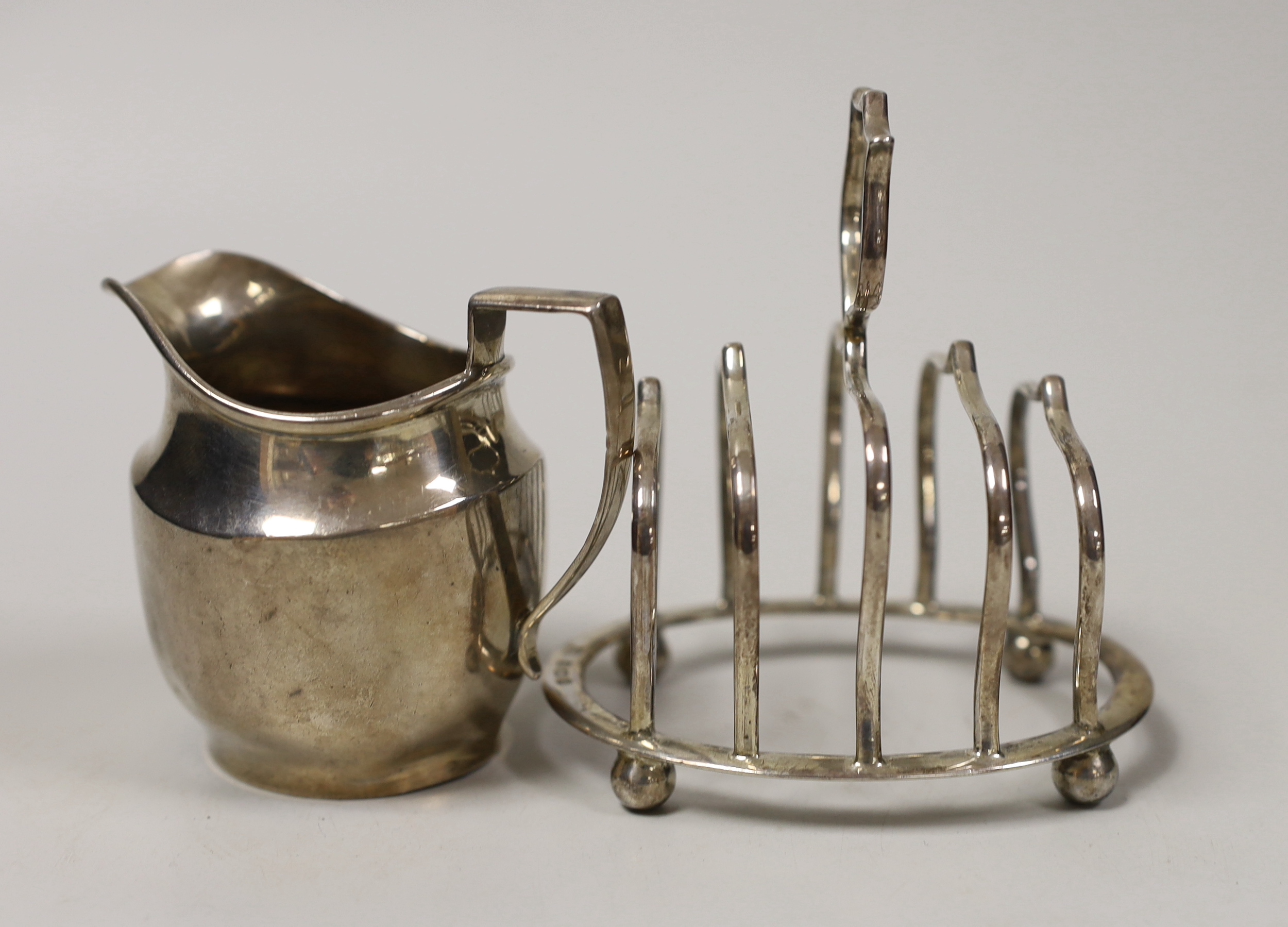 An Edwardian small silver five bar toast rack, Birmingham, 1906, length 94mm and a later silver ceam jug by George Unite, 5.1oz.